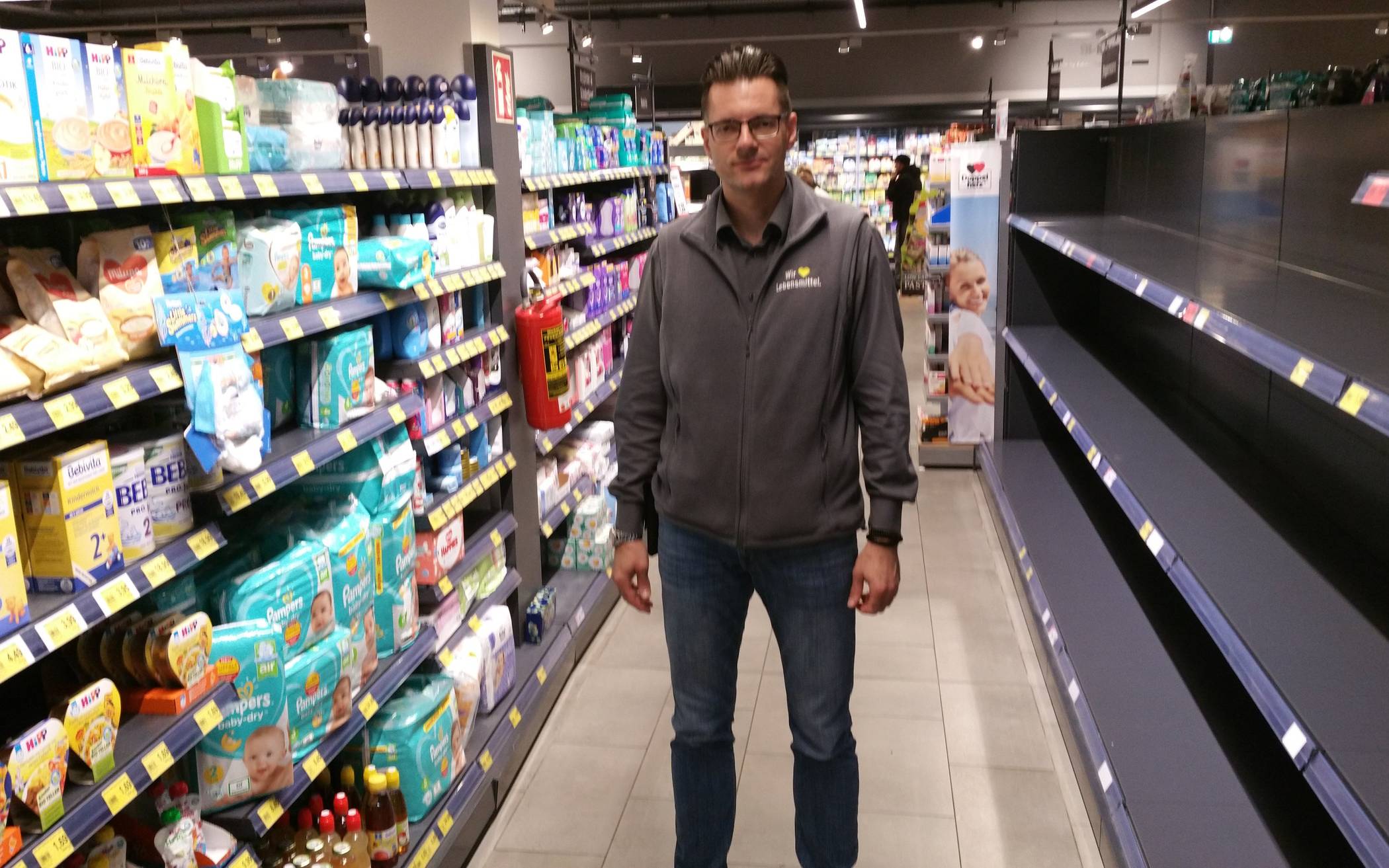  Supermarktinhaber Carsten Paul zwischen vollen und leeren Regalen. 
