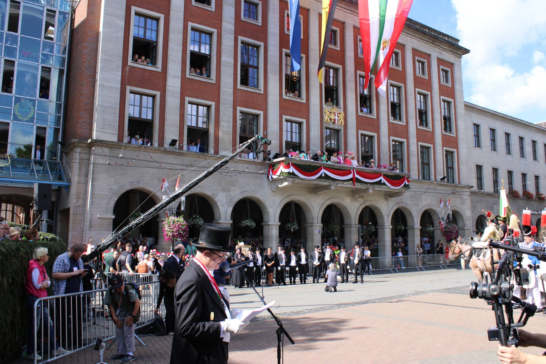 Auf dem Markt herrscht anlässlich der Königsparade regen Treiben; die Rede des Schützenpräsidenten ist einer der Programmpunkte.  
