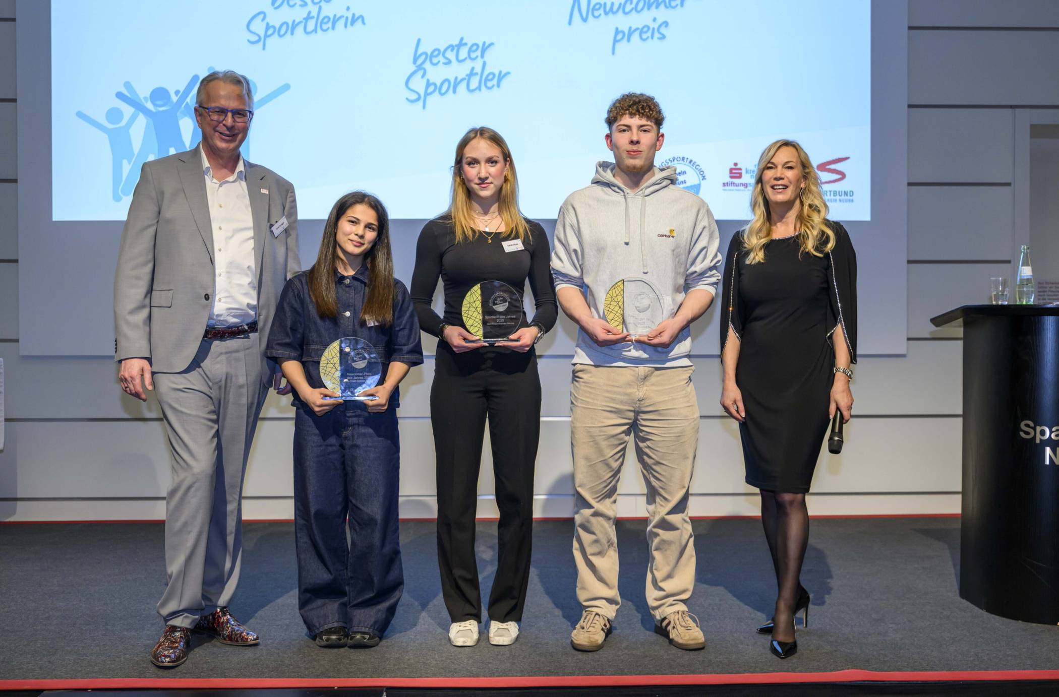  Kreisdirektor und Kreis-Sportdezernent Dirk Brügge mit (v.l.) mit Madina Bayramova (Newcomerpreis 2025), Sarah Dicks (Siegerin der Wahl zur besten Sportlerin 2025), Fabian Mager (Sieger der Wahl zum besten Sportler 2025) und Moderatorin Birgit von Bentzel. 