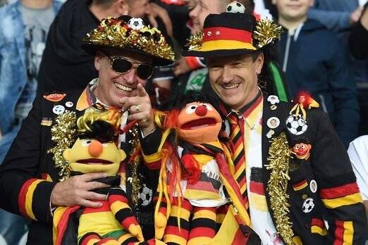 Stefan Vollmert und Andreas Preuss (von links) in ihren Deutschland-Fananzügen und Maskottchen Ernie und Bert: So sah man sie auf zahlreichen Fußball-Weltmeisterschaften, doch diesmal bleiben sie zuhause.   