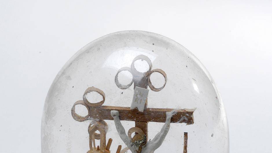 Ein Glassturz mit einer Kreuzigungsszene und den Arma...