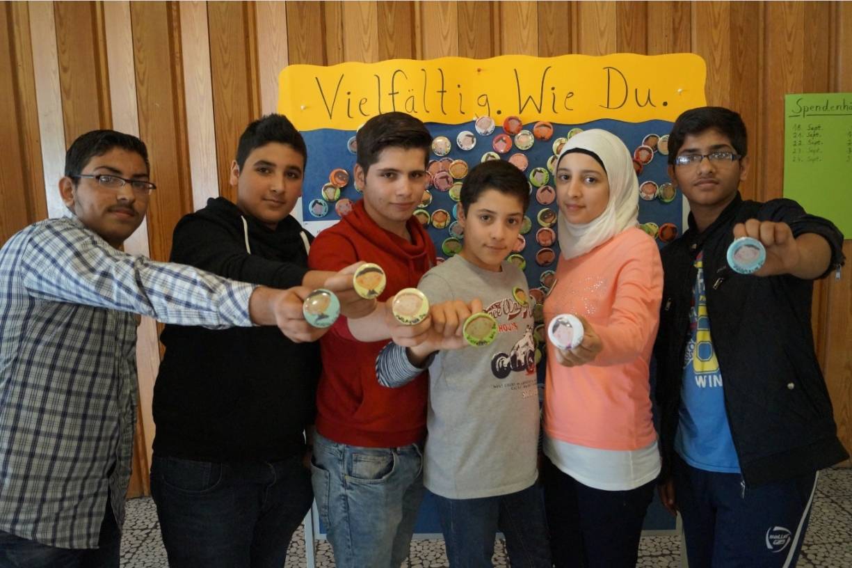  Diese sechs Jugendlichen aus Syrien und Afghanistan leben in Kaarst. Sie präsentieren die Buttons, die zum Motto „Vielfältig. Wie du.“ an der Elisabeth-Selbert-Realschule gebastelt wurden. Jetzt werden die Anstecker für einen Euro verkauft. Der Erlös soll Flüchtlingen zugute kommen. 