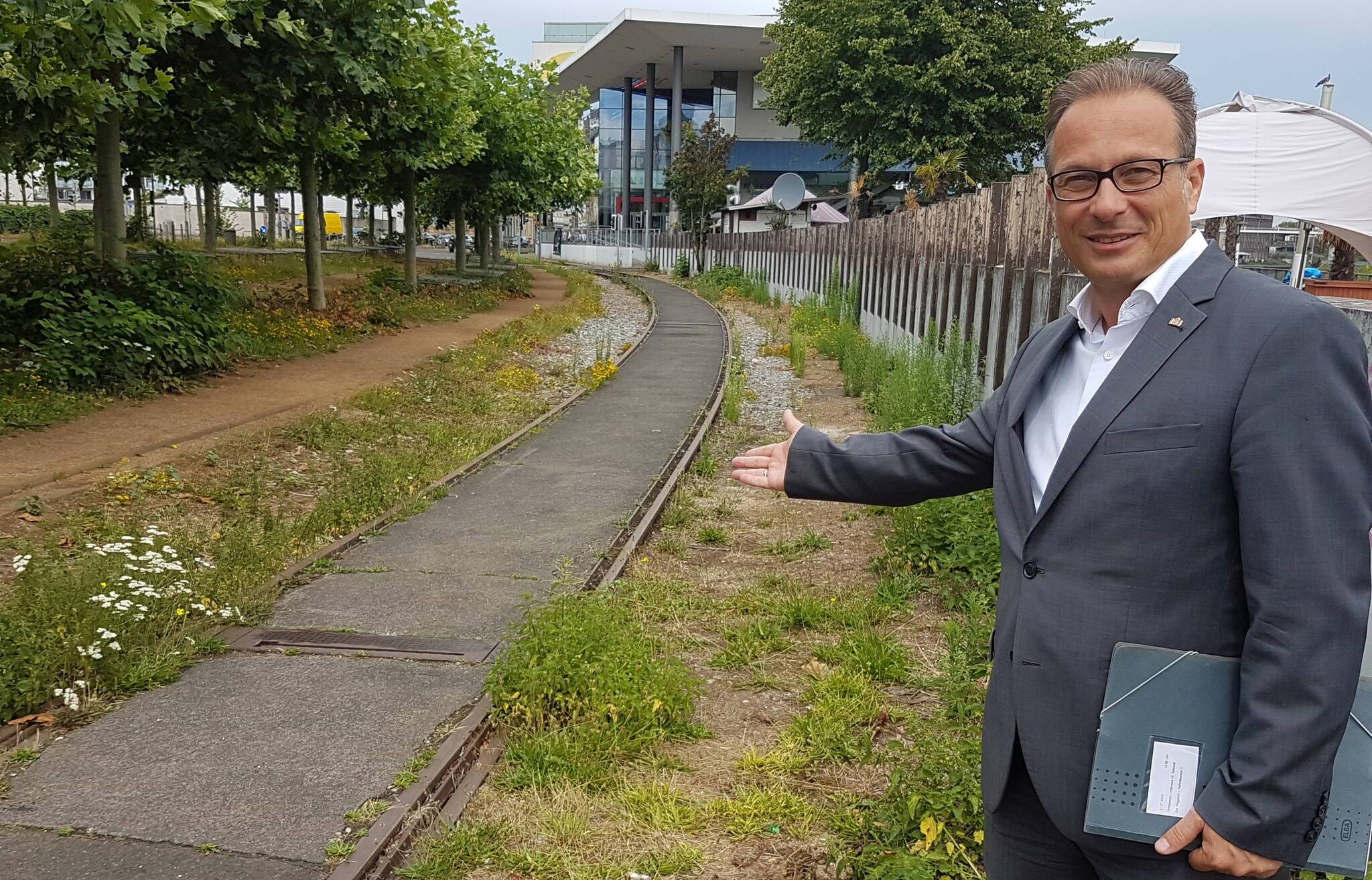  Hier wächst zurzeit Gras über die Sache: Bürgermeister Reiner Breuer am Notgleis, dessen Trasse für die Straßenahn genutzt werden könnte (im Hintergrund UCI-Kino). 
